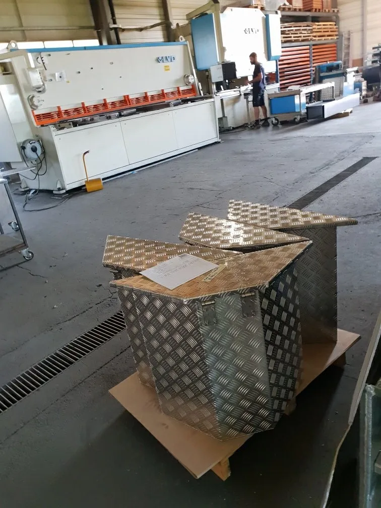 Fertige Transportkiste aus Aluminium-Riffelblech mit Scharnierdeckel vor der Tafelschere