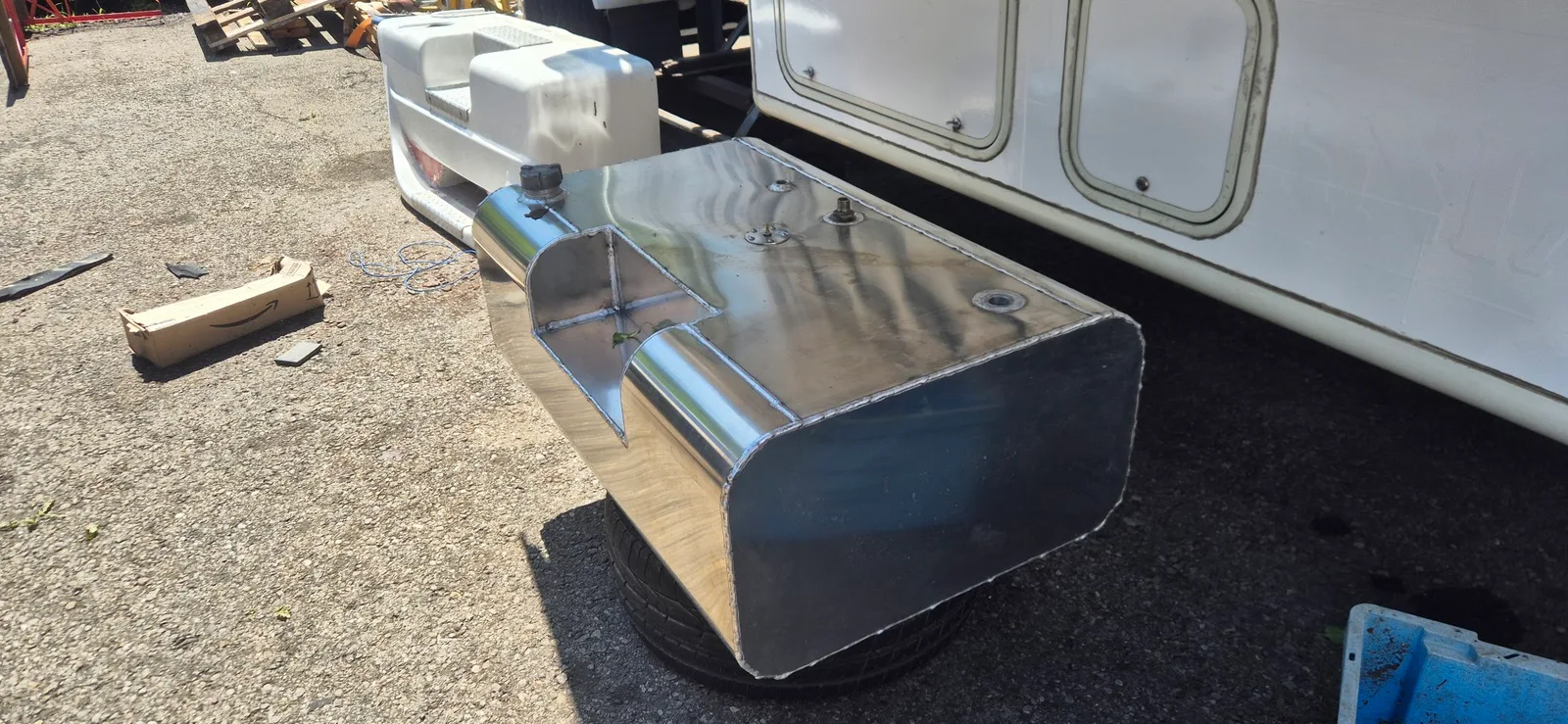 Angefertigter Aluminiumtank mit Schweißnähten und Einfüllstutzen neben einem Fahrzeug